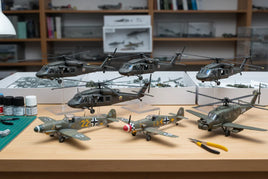 Premium 1/35 scale model aircraft kits including Academy Black Hawks, Border Model WWII fighters, and AFV helicopters displayed on workbench with modeling tools