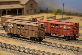 HO scale stock cars on model train tracks with barn, perfect for MPM Hobbies enthusiasts
