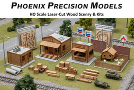 HO scale laser-cut wood model buildings and scenery kits by Phoenix Precision Models on display, including miniature houses, crates, tanks, chicken coop, and train tracks at MPM Hobbies.