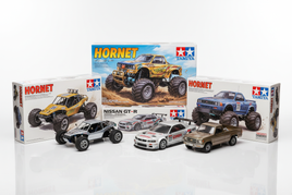 Tamiya model cars and trucks kits, including Hornet and Nissan GT-R, on white background at MPM Hobbies.