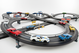 Dynamic HO scale slot car racing scene with colorful vintage muscle cars, Speed Racer vehicles, and rally cars on curved black tracks with bridges, banked turns, and crossovers showing exciting competitive racing action