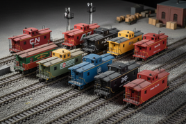 HO scale model train cabooses in various colors on tracks, ideal for MPM Hobbies collectors
