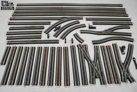 O scale 3 rail model train track pieces assortment, curved and straight, on gray background