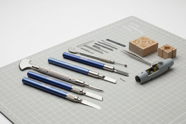 Precision hobby knives, tweezers, and model parts on a cutting mat for scale modeling