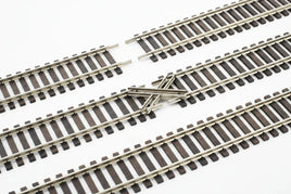 Model train track crossing with metal rails and wooden ties on white background