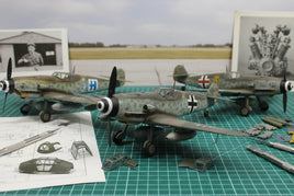 Detailed model WWII fighter planes with assembly parts on workbench, MPM Hobbies display