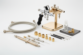 Professional airbrush accessories including precision needles, nozzles, air caps, hoses, and cleaning tools on white background