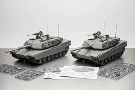 Two gray scale model tanks with assembly sprues and instruction sheets on a tabletop, MPM Hobbies