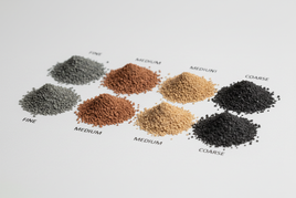 Assorted piles of hobby modeling terrain materials in fine, medium, and coarse grades on white background
