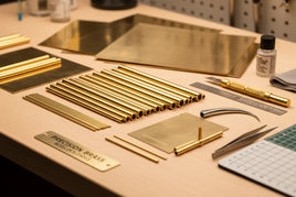 Precision brass rods, sheets, and hobby tools arranged on a workbench at MPM Hobbies