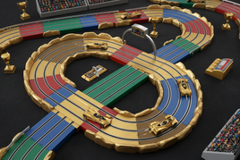 HO scale slot car racing set with miniature cars on a gold-themed circuit track with lap counter accessory, representing Auto World racing sets and accessories at MPM Hobbies.