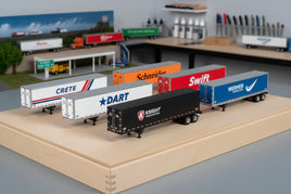 Assorted model truck trailers with detailed brand logos on display at MPM Hobbies workspace