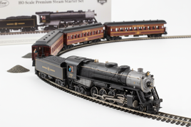 HO scale model train sets including steam and diesel locomotives with passenger and freight cars showing detailed paint schemes on white surface for ready-to-run model railroad starter sets