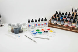 Assorted model paint bottles, jars, and paint tools on a white table at MPM Hobbies store.