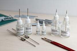Precision plastics cement bottles, applicators, and paintbrushes for model building on table