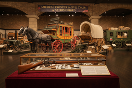 American frontier museum display with stagecoach, covered wagon, Civil War artifacts, and vintage rifle