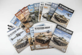 Assorted Mig Jimenez modeling magazines featuring tanks and aircraft, with paint bottles and brushes.
