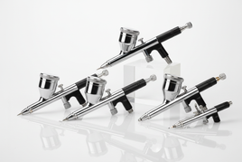 Professional dual-action gravity-feed airbrushes with chrome and black finishes displaying precision nozzles for scale modeling