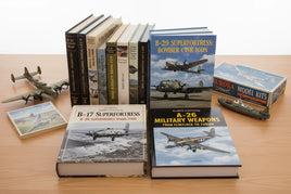 Schiffer Publishing military aircraft books, model planes, and Aurora model kit on wood table at MPM Hobbies