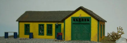 Model of a yellow building with green doors on a plain background