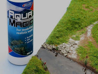 Can of Aqua Magic spray for modeling realistic water next to a miniature landscape with a road and grass.