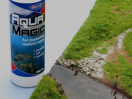 Can of Aqua Magic spray for modeling realistic water next to a miniature landscape with a road and grass.