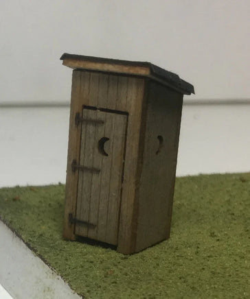 Small wooden model of a shed on a green surface with a white background