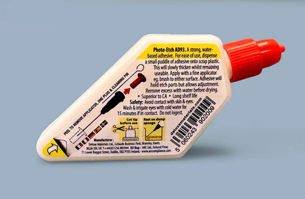 Adhesive bottle with red cap and white label on a gray background
