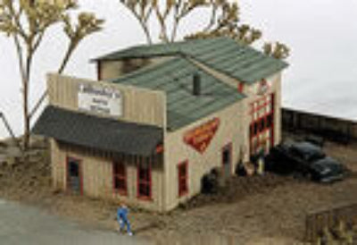 Model of a small building with a green roof and a person standing nearby.