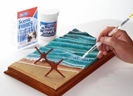 Hand painting a scenic landscape on a book with 'Scenic Fibres' and 'Making Waves' products.