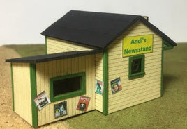 Model of a newsstand with a sign reading 'Andi's Newsstand' on a plain background