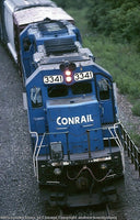 Blue Conrail train engine on a track with greenery in the background