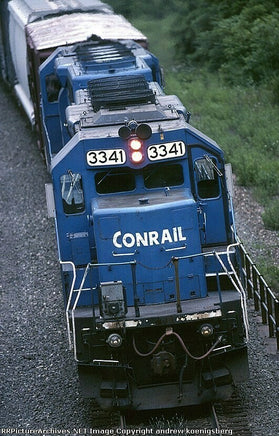 Blue Conrail train engine on a track with greenery in the background