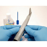 Person wearing blue gloves holding a metal tool with a white background