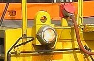 Close-up of a yellow vehicle light and red hose on an orange background