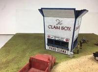 Model of a building labeled 'The Clam Box' with people and a truck in front on a green and brown surface.