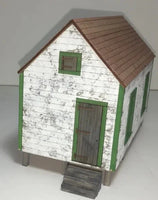 Model of a small wooden house with a brown roof on a white background
