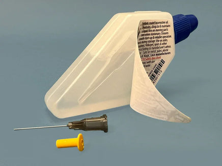 Plastic tool with a blue cap, white container, and small yellow object on a gray background