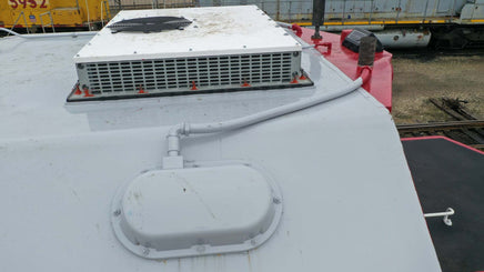 Roof-mounted air conditioning unit on a vehicle with a train in the background