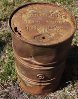 Rusty metal barrel with visible branding on a grassy background