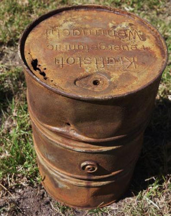 Rusty metal barrel with visible branding on a grassy background