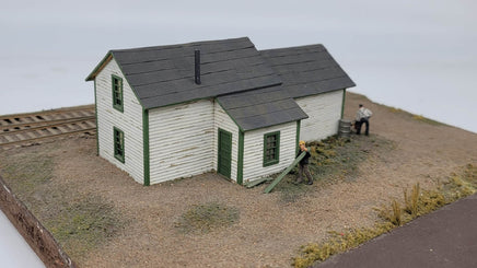Model of a small building with green doors and gray roof on a plain background