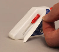 Hand holding a white plastic tool with a red screwdriver-like component on a beige background