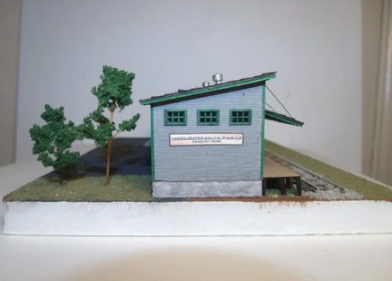 Model of a small building with trees on a white surface