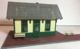 Model of a small building with a green roof and yellow walls on a white background