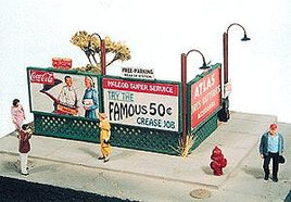 Model of a vintage gas station with people and signs, featuring a Coca-Cola sign.