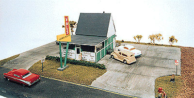 Model of a small building with cars and a red car in front, on a clear background