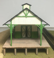 Model train station with green and beige structure on a platform