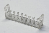 Clear plastic test tube rack with small cylindrical objects on a light gray background