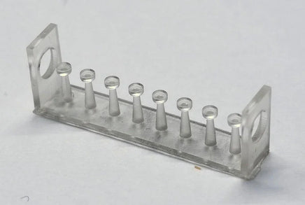 Clear plastic test tube rack with small cylindrical objects on a light gray background